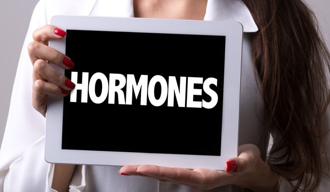 woman holding a hormones sign to teach what are hormones?